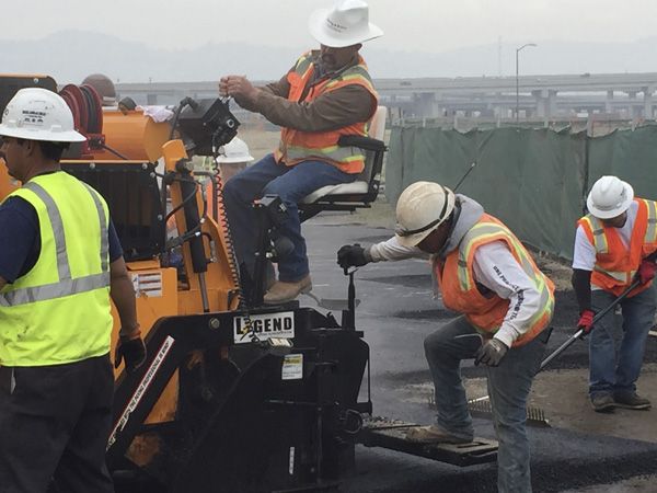 outside construction workers on machinery on concrete/ paving